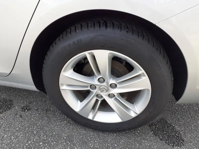 Gros plan sur la roue avant gauche d’une Opel Insignia Grand Sport gris clair, jante alliage à cinq branches doubles.