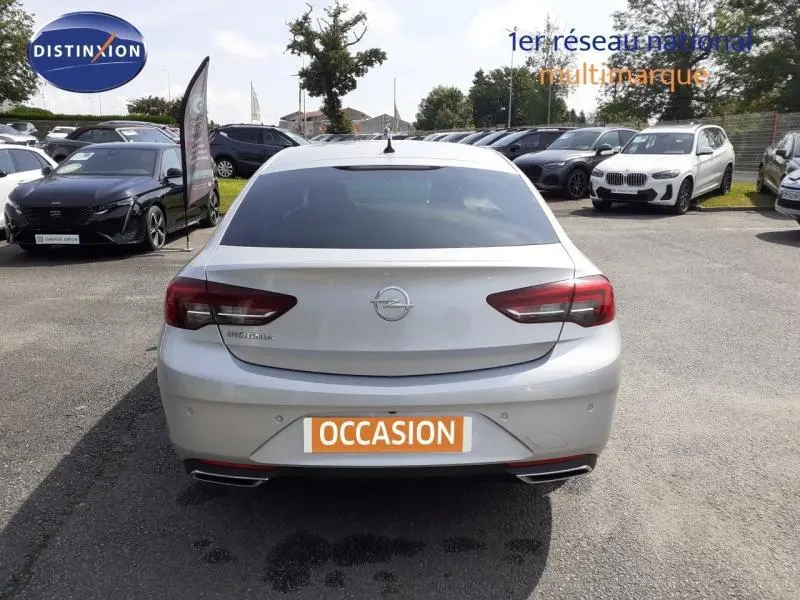 Vue arrière d'une Opel Insignia Grand Sport gris clair 2021 avec feux LED et plaque d'occasion visible sur un parking.