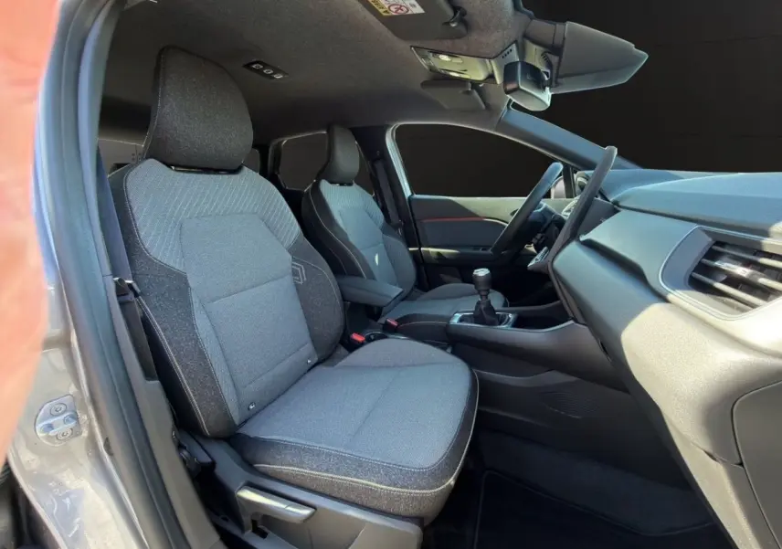 Vue intérieure côté conducteur de la Renault Captur gris foncé 2024, sièges tissu et volant multifonctions.
