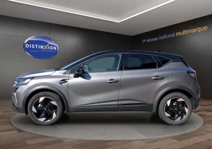 Profil côté gauche du Renault Captur techno TCe 90 gris foncé 2024 avec jantes bicolores et lignes noires contrastantes.