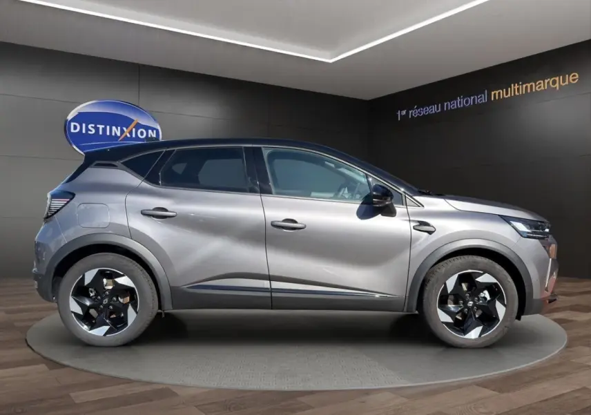 Profil droit du Renault Captur Techno TCe 90 gris foncé avec jantes noires et détails chromés visibles en showroom.