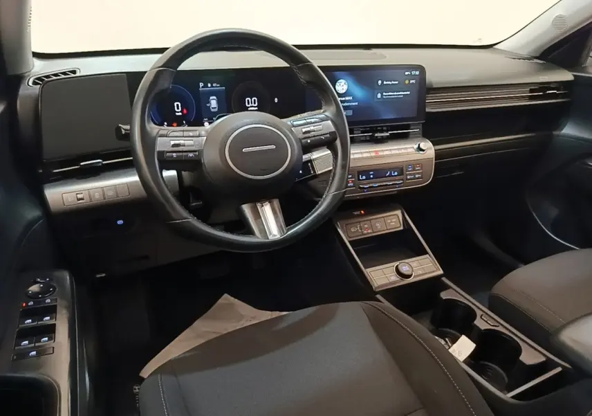 Intérieur noir de la Hyundai Kona 2024, vue depuis le siège conducteur avec volant cuir et écran tactile central.