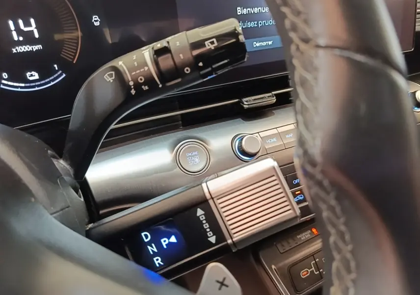 Vue rapprochée de l’intérieur du Hyundai Kona 2024 hybride, montrant le volant cuir et la commande de boîte automatique éclairée.