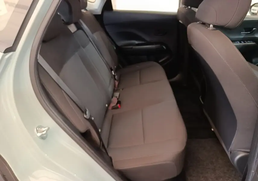 Vue intérieure côté gauche montrant la banquette arrière grise du Hyundai Kona 1.6 Hybrid 2024 vert pâle.