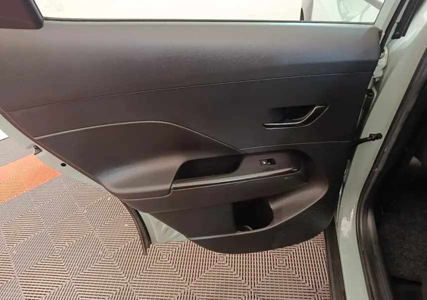 Vue intérieure sur la porte arrière gauche noire du Hyundai Kona 1.6 Hybrid 2024 vert, avec poignée et commande de vitre.