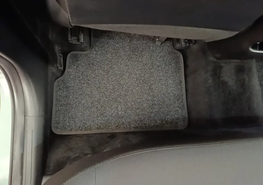 Vue rapprochée du tapis de sol gris foncé côté passager arrière d'un Hyundai Kona vert 2024.