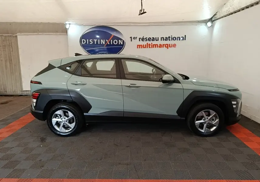 Vue de profil côté gauche d’un Hyundai Kona 2024 vert avec protections noires sur les passages de roues.