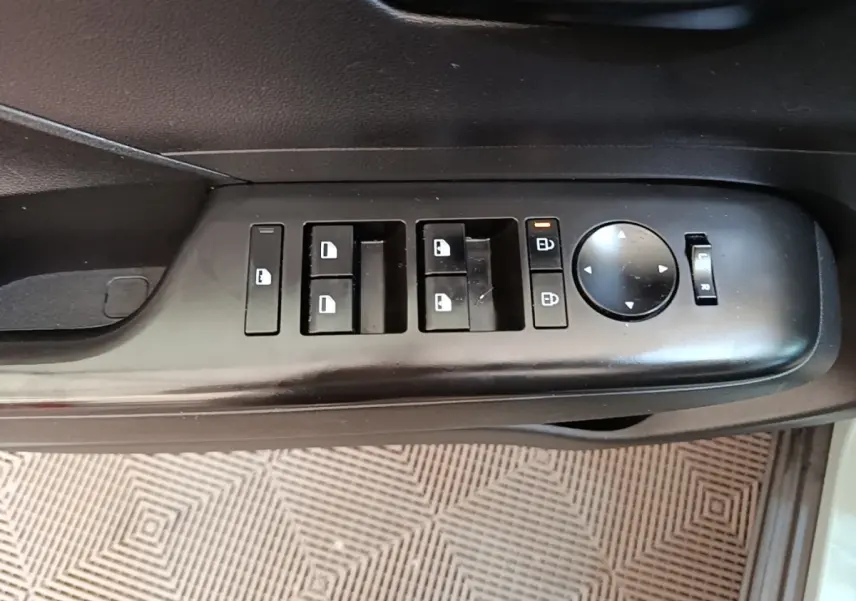 Gros plan sur les commandes de lève-vitres et rétroviseurs côté conducteur d’un Hyundai Kona vert 2024.