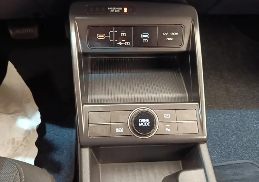 Gros plan sur la console centrale noire du Hyundai Kona 2024, avec commandes Drive Mode et ports USB visibles.