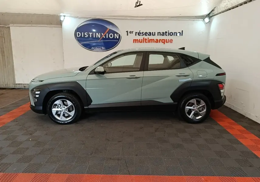 Vue de profil côté gauche d'un Hyundai Kona 2024 vert avec protections noires et jantes alliage cinq branches.