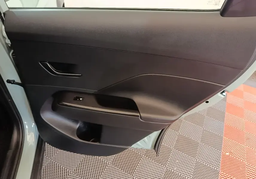 Porte arrière droite ouverte du Hyundai Kona vert, montrant le panneau intérieur noir avec poignée et commande vitre.