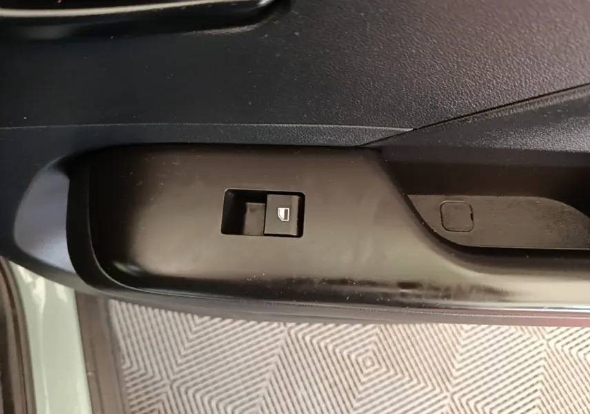 Gros plan sur le bouton de commande de vitre électrique côté conducteur dans une Hyundai Kona 1.6 Hybrid 2024 vert.