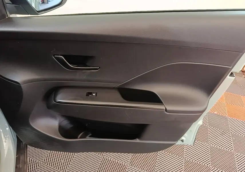 Gros plan sur la porte côté gauche du Hyundai Kona 2024 hybride, montrant la poignée et le panneau de commande noir.