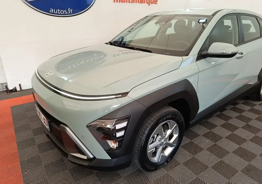 Vue 3/4 avant droite d'une Hyundai Kona 2024 vert clair avec phares LED et protections noires sur les ailes.