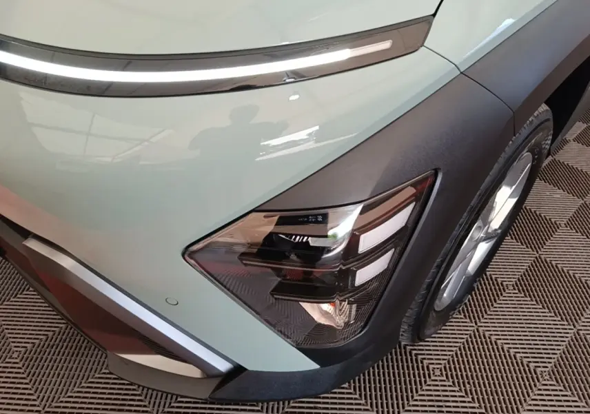 Gros plan sur l'avant droit vert du Hyundai Kona 2024, mettant en valeur le phare LED et la roue.