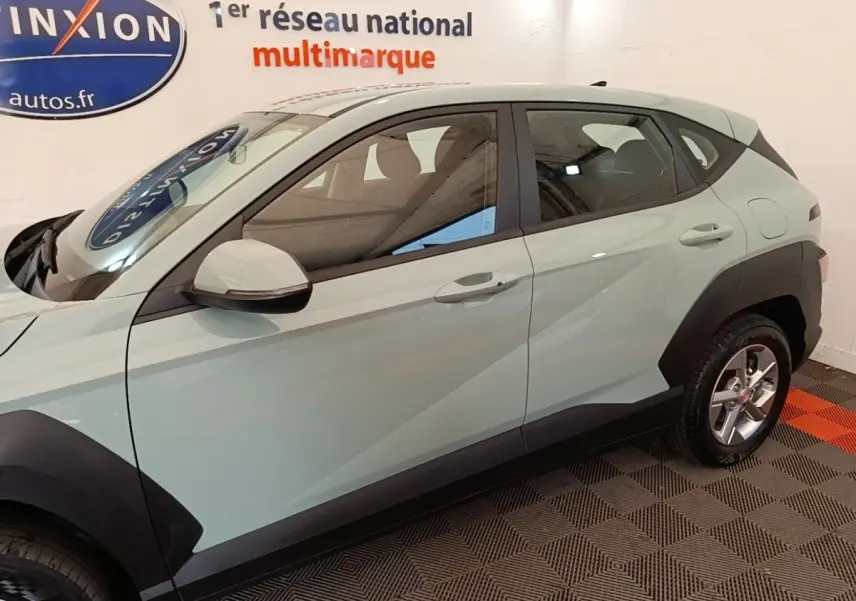 Vue de profil côté gauche d’un Hyundai Kona vert 2024 avec protections noires sur les passages de roues.