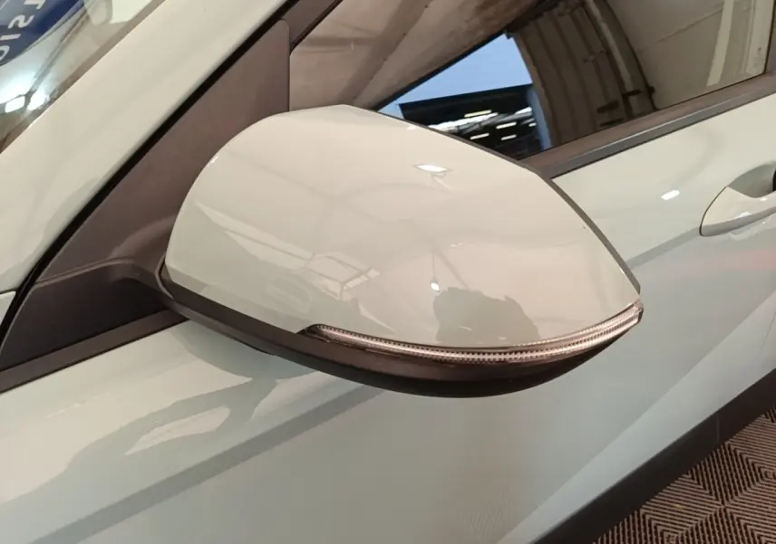 Gros plan sur le rétroviseur droit blanc du Hyundai Kona 2024 hybride, avec clignotant intégré visible.