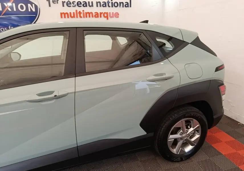 Vue latérale droite d’un Hyundai Kona 2024 vert avec jantes alliage et protections noires sur les ailes.