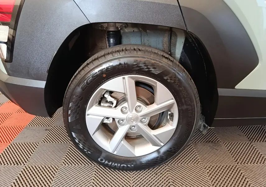 Gros plan sur la roue arrière droite d’un Hyundai Kona vert 2024 avec jante alliage argent et passage de roue noir.
