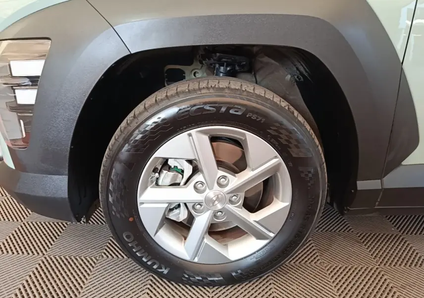 Gros plan sur la roue avant droite d'une Hyundai Kona 2024 verte, avec jante alliage et passage de roue noir mat.