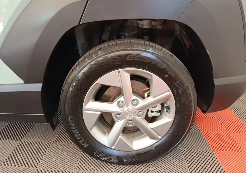 Gros plan sur la roue avant droite du Hyundai Kona vert 2024 avec jante alliage et pneu Kumho Ecsta.