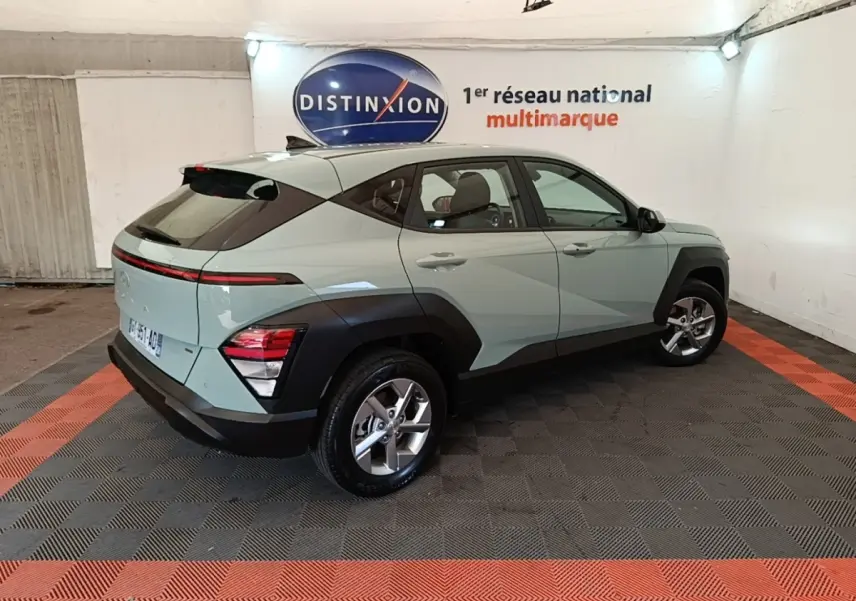 Vue 3/4 arrière droite d'un Hyundai Kona 2024 vert avec arches noires et feux arrière LED fins.