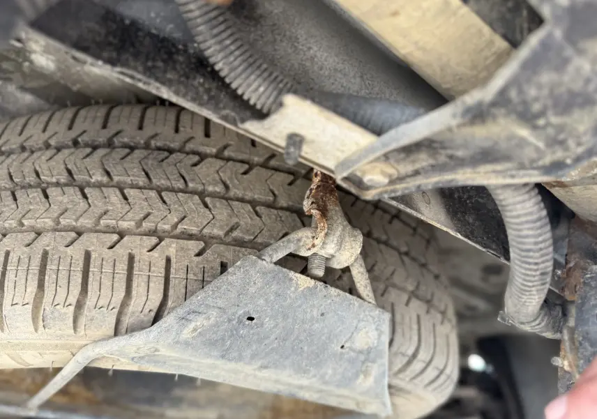 Gros plan sous le Peugeot Expert FGN blanc 2017 montrant la roue de secours et une fixation rouillée.
