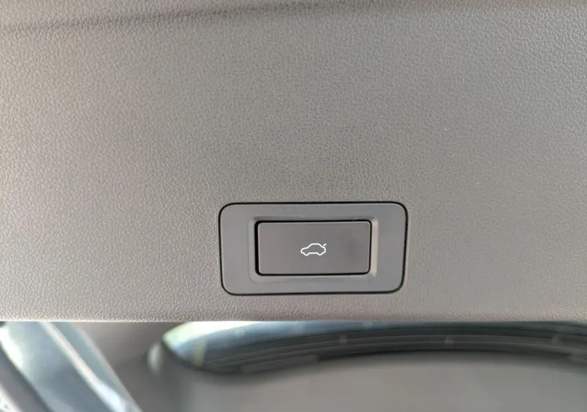 Gros plan sur le bouton d'ouverture électrique du coffre, intégré dans le revêtement intérieur noir du JAECOO J7.