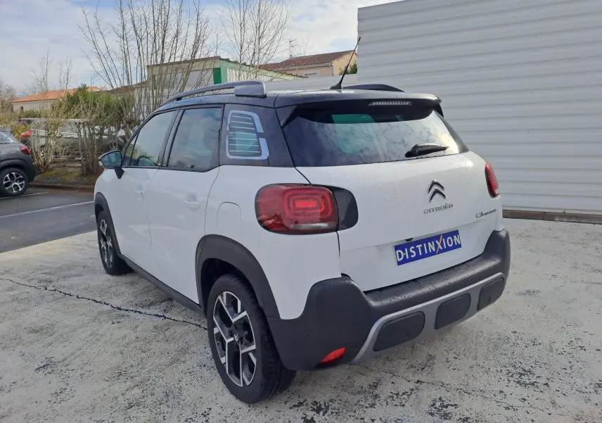 Vue 3/4 arrière droite du Citroën C3 Aircross blanc banquise avec toit noir et feux arrière distinctifs.