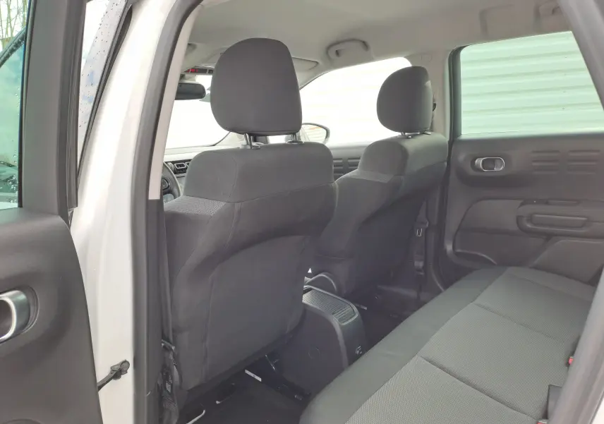 Vue intérieure arrière côté gauche du Citroën C3 Aircross blanc banquise, sièges en tissu gris foncé.