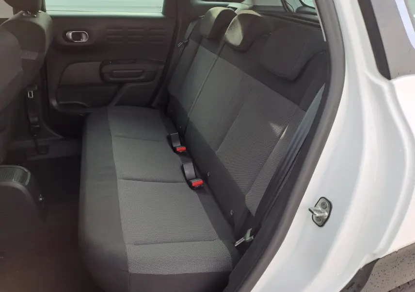 Vue côté gauche de la banquette arrière grise du Citroën C3 Aircross blanc banquise 2024 avec porte ouverte.