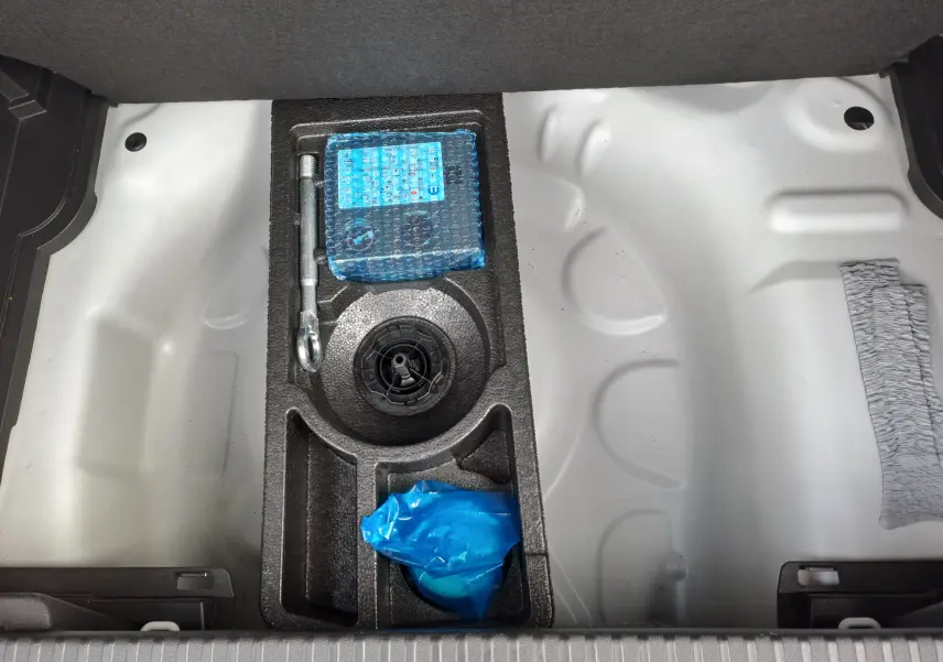 Vue en plongée sur le coffre blanc banquise d'une Citroën C3 Aircross 2024, montrant le rangement d'outils et accessoires.