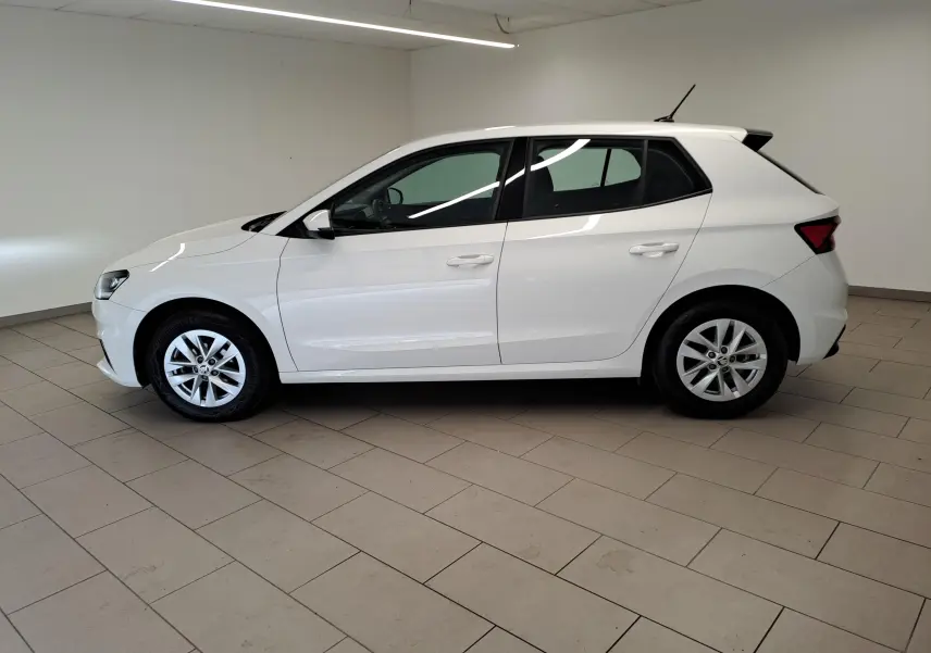 Vue latérale droite d'une Skoda Fabia blanche Candy 2023, finition Ambition, en intérieur sur sol carrelé.