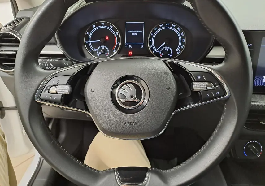 Vue rapprochée du volant multifonction noir de la Skoda Fabia 2023 avec tableau de bord digital allumé.