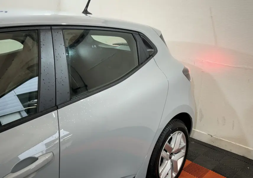 Vue côté gauche arrière d'une Renault Clio gris clair Evolution Blue dCi 100, avec jante alliage et antenne toit visible.