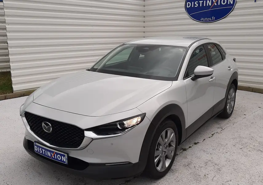 Vue 3/4 avant droite d'un Mazda CX-30 2024 blanc céramique avec calandre noire et feux LED allumés.