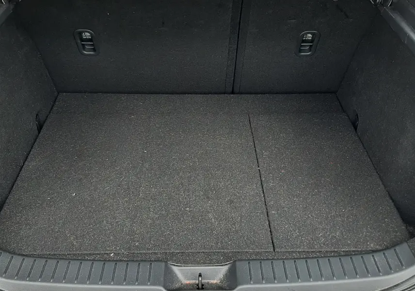 Vue du coffre ouvert d'une Mazda CX-30 blanche, montrant un espace de chargement propre et tapissé en noir.