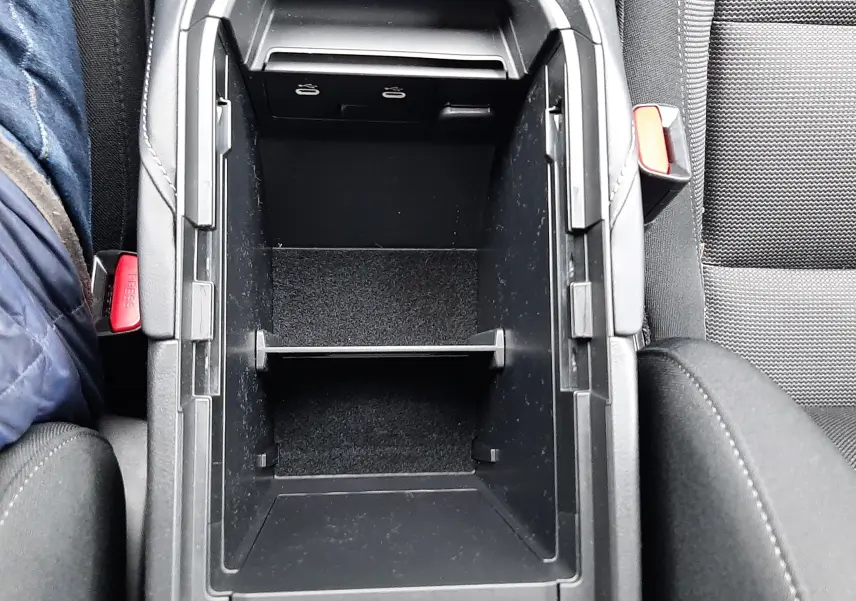 Vue plongeante sur le rangement central noir ouvert entre les sièges avant d'une Mazda CX-30 2024.