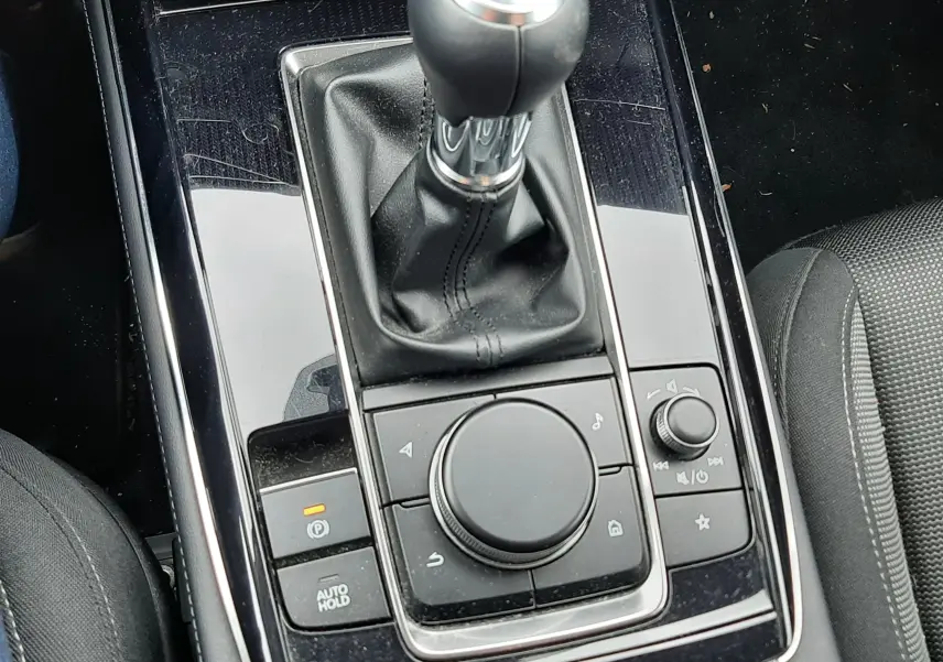 Vue rapprochée de la console centrale noire avec levier de vitesse manuel et commandes multimédia d’une Mazda CX-30 2024.