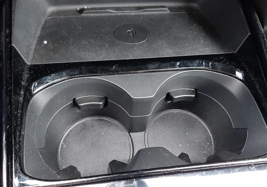 Gros plan intérieur sur les porte-gobelets noirs et le chargeur sans fil de la Mazda CX-30 2024 Ceramic White.