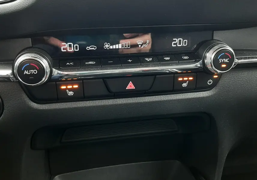 Détail du tableau de bord du Mazda CX-30 2024 en Ceramic White, affichant la climatisation automatique et sièges chauffants.