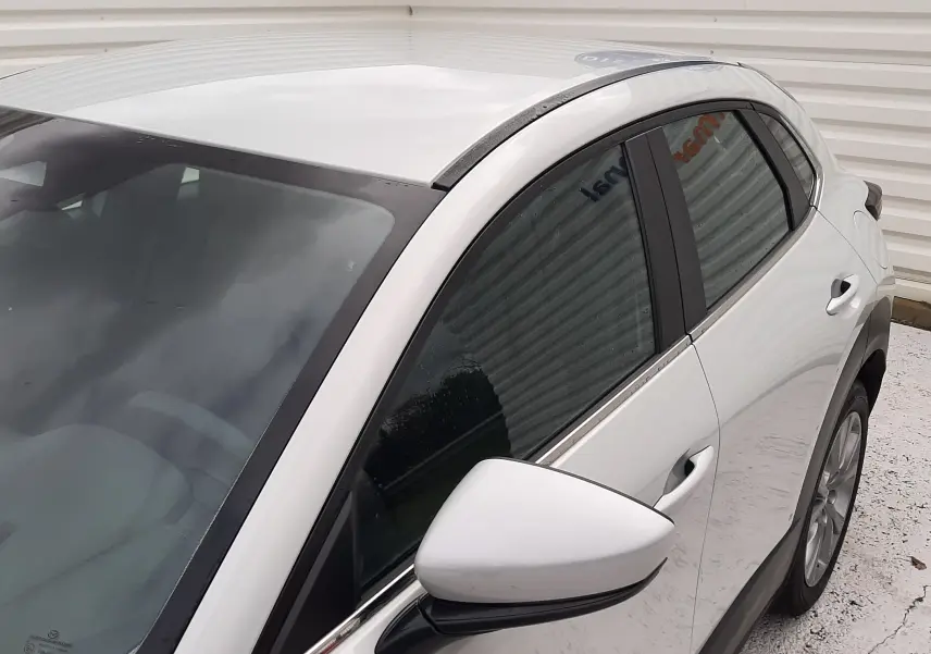 Vue 3/4 avant droit du Mazda CX-30 blanc Ceramic, mettant en valeur la ligne de toit et le rétroviseur latéral.