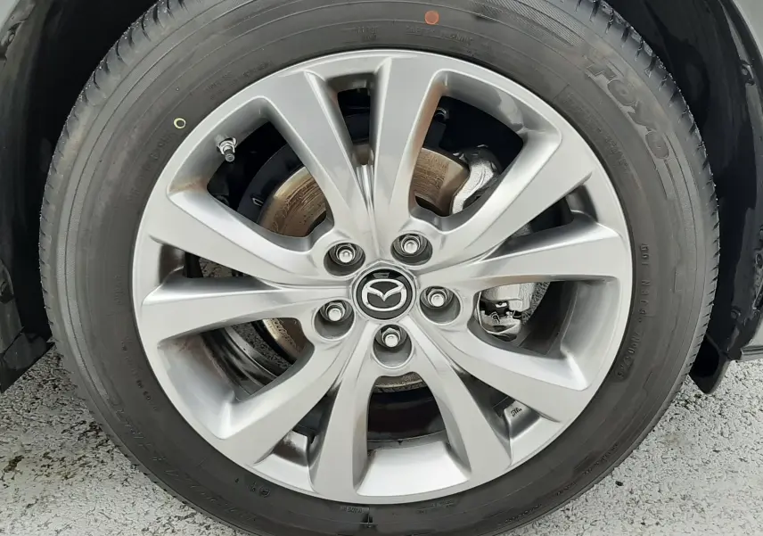 Gros plan sur la roue avant droite du Mazda CX-30 2024 en blanc céramique avec jante alliage 18 pouces et logo Mazda central.