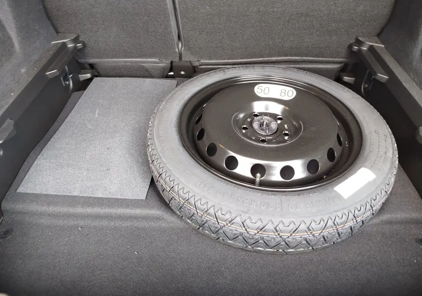 Vue rapprochée du coffre du Renault Symbioz 2025 montrant la roue de secours noire posée sur le tapis gris.