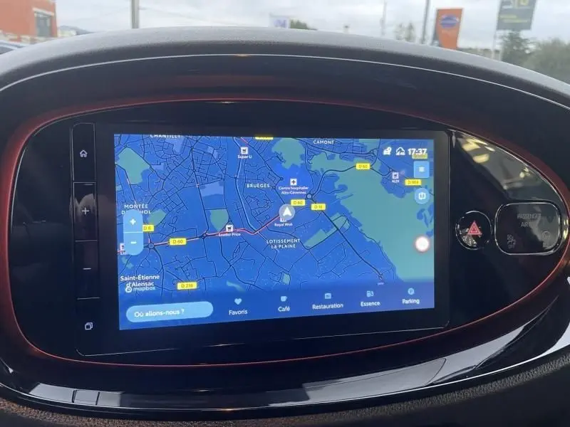 Écran tactile central du tableau de bord de la Toyota Aygo X 2023, avec contour rouge piment et toit noir visible en reflet.