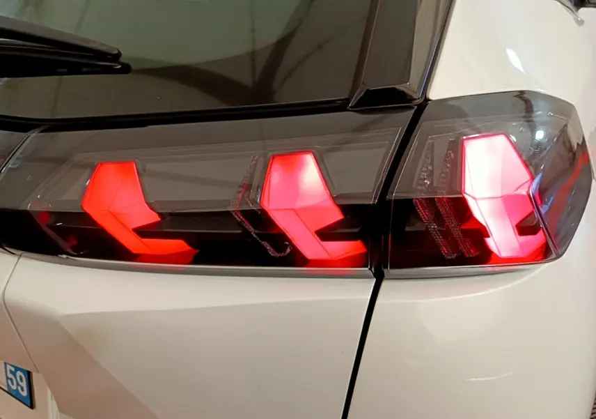 Gros plan sur les feux arrière allumés du côté gauche d’un Peugeot 2008 blanc, version 2021.