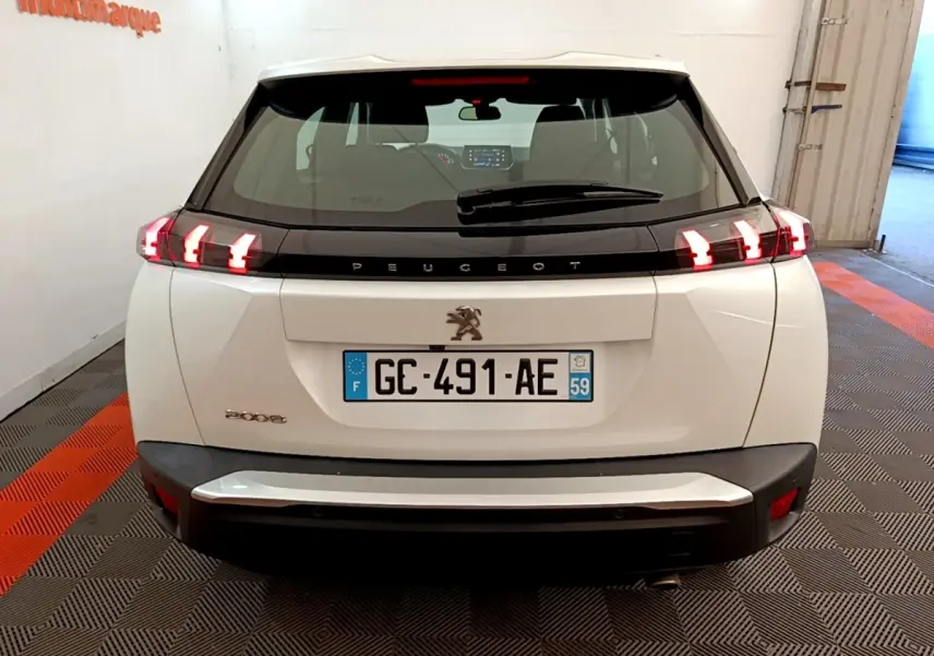 Vue arrière d'un Peugeot 2008 blanc avec feux LED allumés dans un garage fermé.