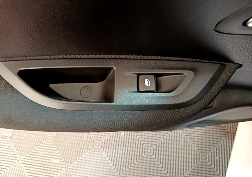 Gros plan sur la commande d'ouverture de trappe à carburant noire à l'intérieur d'une Peugeot 2008 blanche.