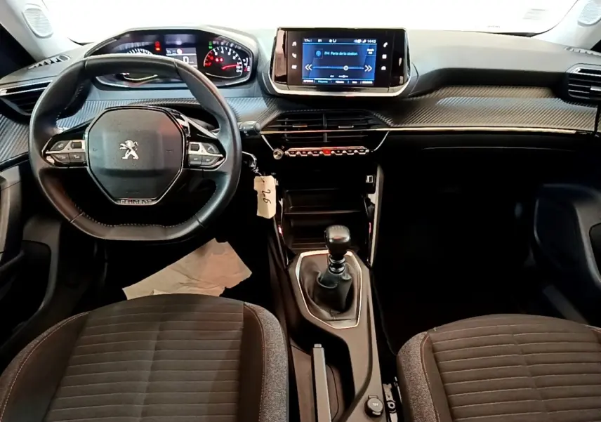 Vue intérieure du tableau de bord et volant cuir de la Peugeot 2008 1.5 BlueHDi, avec écran tactile central et boîte manuelle.