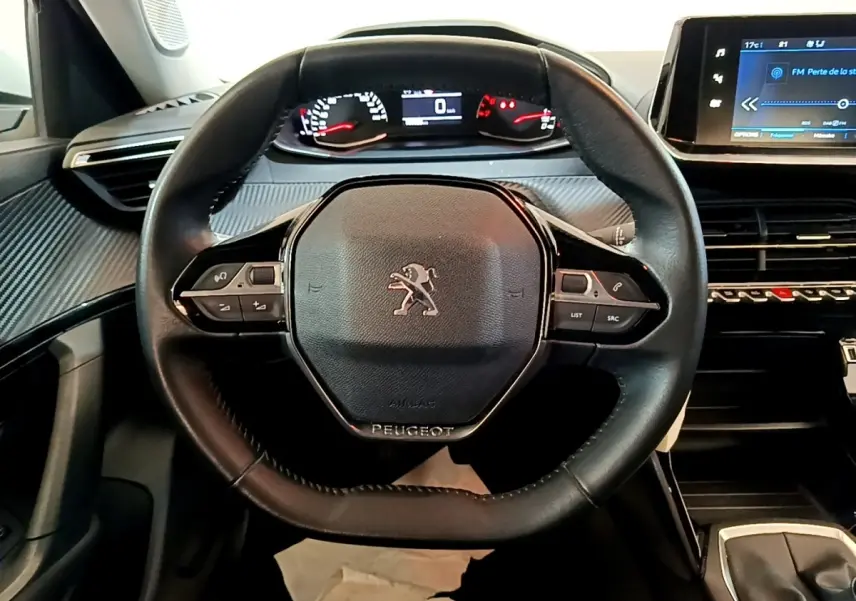Vue intérieure centrée sur le volant cuir noir de la Peugeot 2008 avec tableau de bord digital et écran tactile.